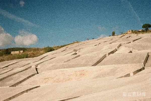 高清摄影 阶梯状的山丘，有混凝土建筑，蓝天映衬