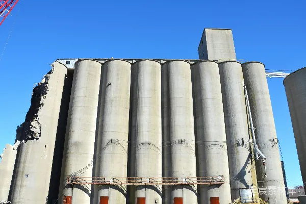 高清摄影 混凝土筒仓在蓝天之下，某部分受损。