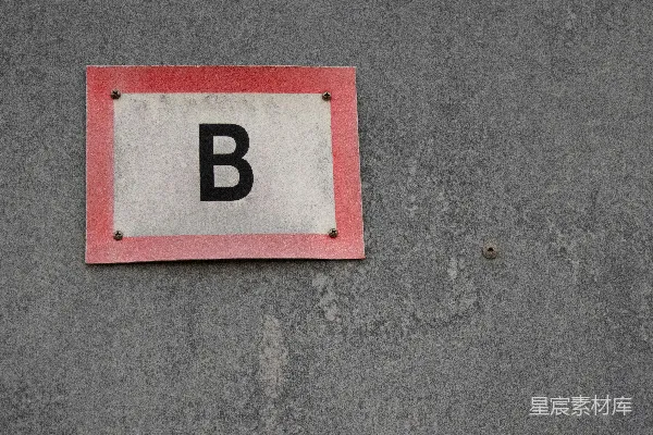 高清摄影 灰色墙上有红色边框的标志，上面有一个黑色的“b”。
