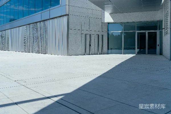 高清摄影 现代化建筑入口，旁边有一个混凝土广场，阴影浓重。