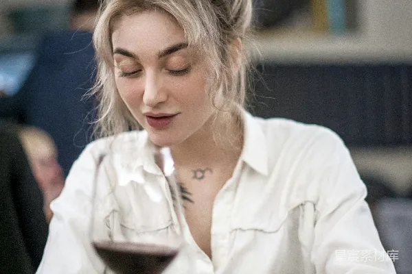 白裙女子手持透明酒杯