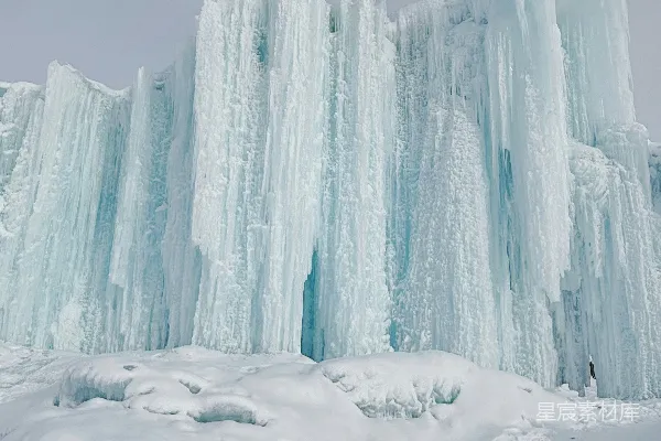 一座高耸入云的冰山矗立在覆盖着白雪的土地上。