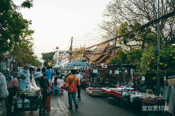 一群人在一条街道上步行，旁边是市场