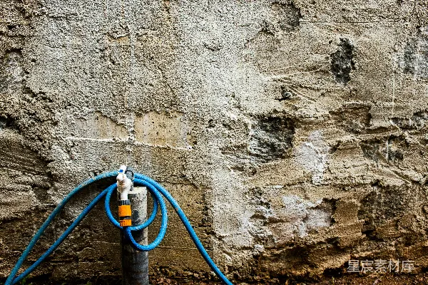 高清摄影 蓝色的软管缠绕在水龙头上，背景是纹理墙面。
