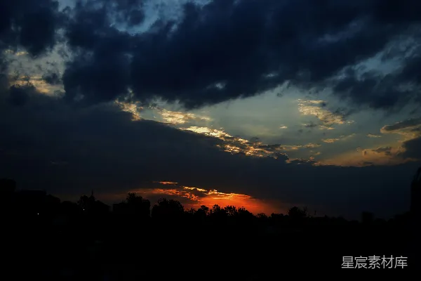 夕阳落在一片乌云密布的天空后面