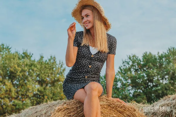 穿着黑白条纹连衣裙的穿褐色稻草的女人坐在那里。