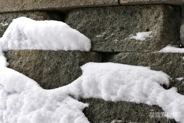 高清摄影 一条被雪覆盖的石墙靠近人行道。