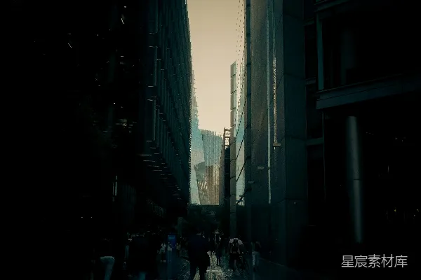 高清摄影 一群人沿着高楼旁的街道行走。