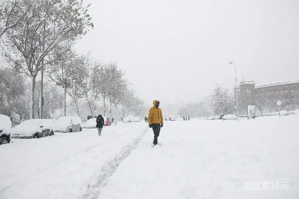 黄色夹克的人在雪地覆盖的地面上行走，白天。