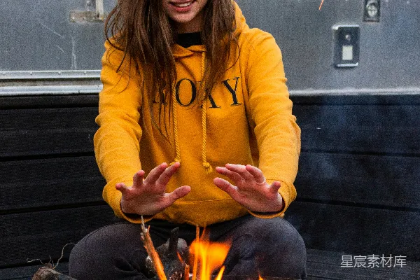 黄色夹克的女人手持一根带有火焰的棍子