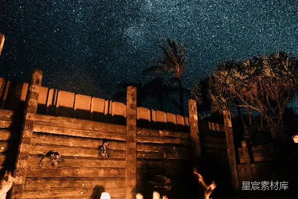 一群人在满天繁星的夜空下围着篝火坐着。