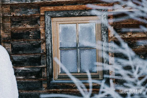 地面上覆盖着白雪的小木屋和一扇窗户
