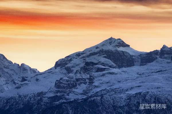 山脚下覆盖着白雪，背景是夕阳西下。