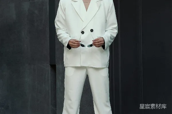 一身白西装的男人站在一座建筑物前