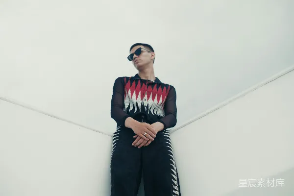 身穿黑色和红色衣服的男子倚靠在墙上