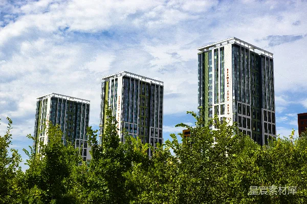 三座现代高层建筑背后有绿树。