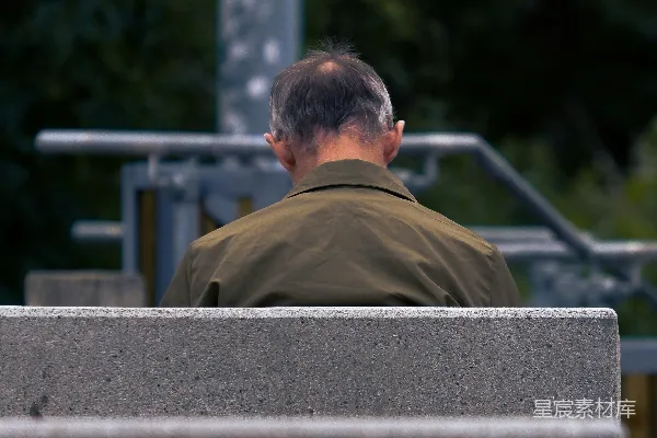 高清摄影 一个男人坐在水泥长凳的顶端。