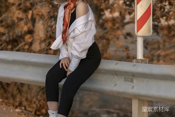 一个女人坐在路边的栏杆旁