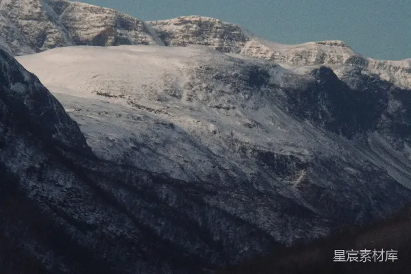 山峦被白雪覆盖，前景中有树木。