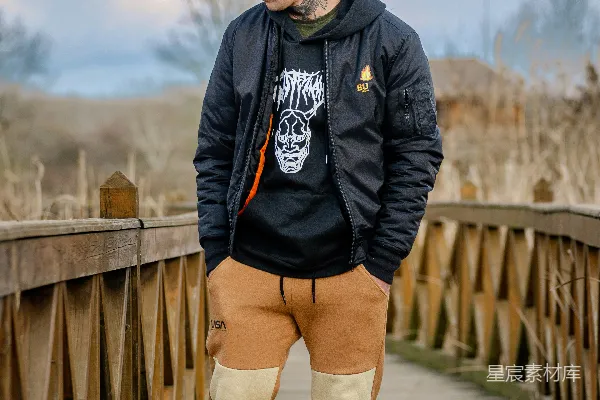 一个男人站在一座木质桥上，手插在口袋里。