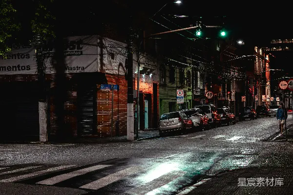 夜晚街道场景中有停放的车辆和交通灯。