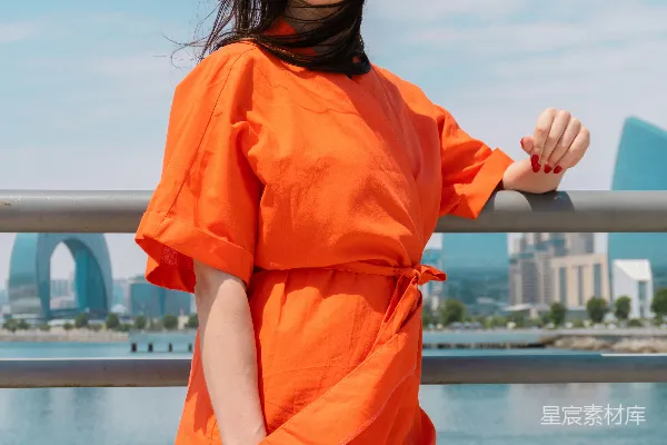 橙色紧身上衣的年轻女子户外戴着太阳镜