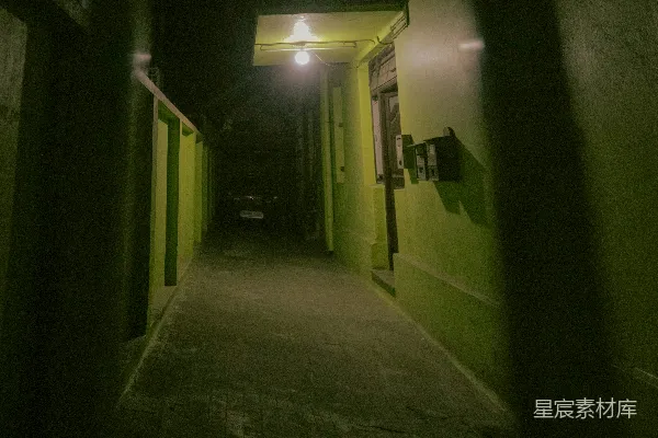 夜晚一条狭窄的巷道，墙壁是绿色的。