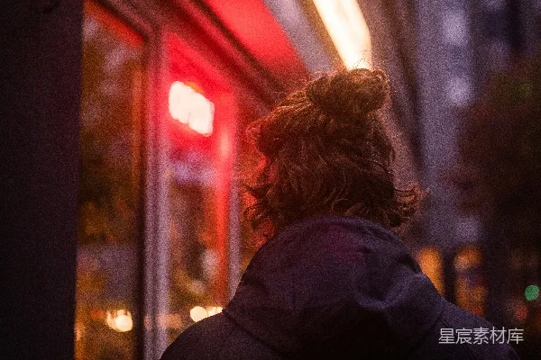 黑色风衣女站在夜晚靠近玻璃窗的地方
