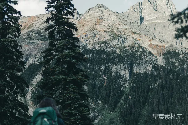 穿着绿夹克的人在覆有白雪的山峦附近白天站立