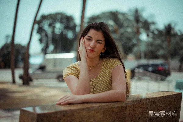 黑白条纹上衣着装女性靠在褐色混凝土墙边
