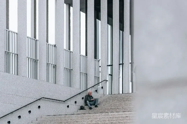 高清摄影 一个男人坐在一幢建筑前的楼梯上。