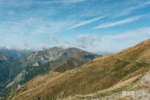 白天绿山、褐山、蓝天和白云之间