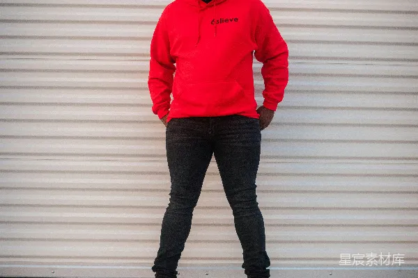 身穿红毛衣的男人站在白色墙壁旁