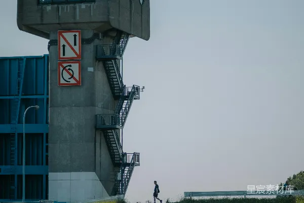 高清摄影 一个人走上一座粗犷建筑旁的混凝土楼梯。