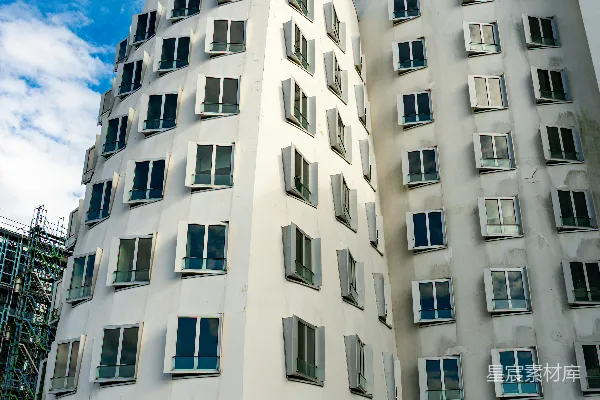 现代白色建筑在蓝天白云下有许多窗户。