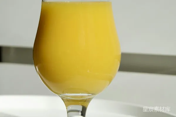 一杯橙汁放在白色的桌子上。