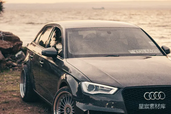 一辆时尚的 Audi 停放在日落海滩上。