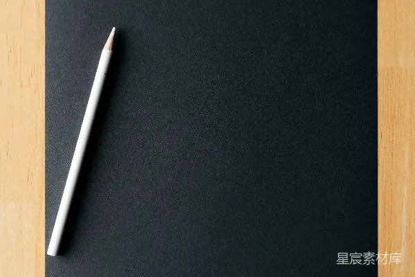 高清摄影 一支白色的铅笔放在一张空白的黑色纸上。