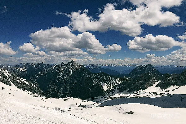 白天雪山覆盖着白雪，云朵漂浮在蓝天中