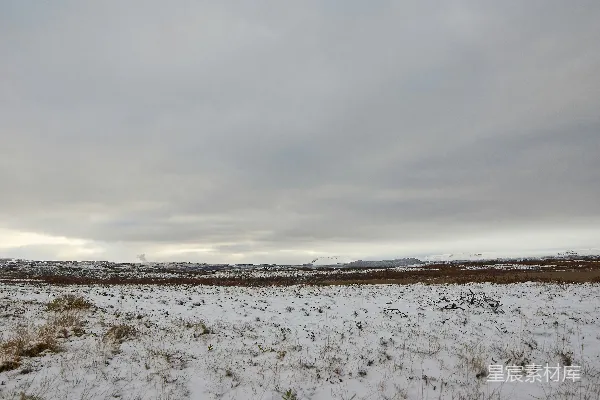 覆盖着白雪的田野远处是山峦。