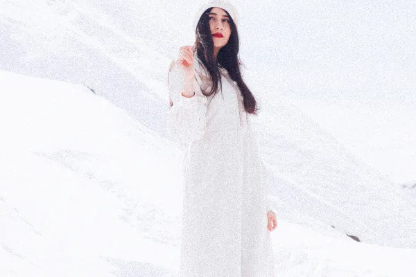 一个女人站在雪地里穿着白色风衣。