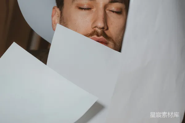 高清摄影 闭着眼睛的男人被飞舞的纸片包围着。