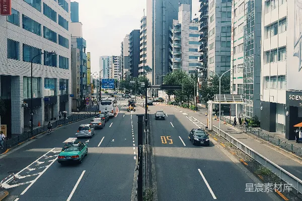 路旁近高楼的汽车在白天行驶。