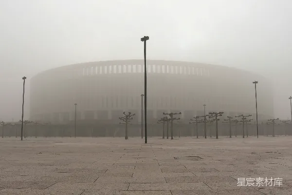 背景有一座大建筑的雾蒙蒙停车场。