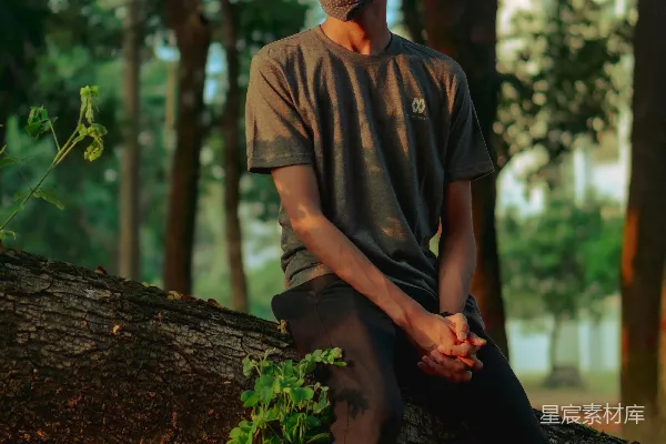 一个男人坐在树干上，戴着口罩。
