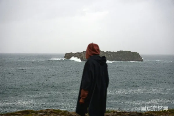 山顶上站着一个人，旁边是海洋。
