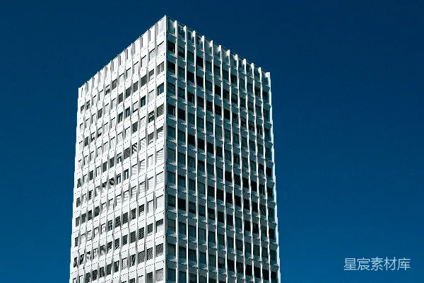 一座高大的白色建筑紧挨着一个交通灯。