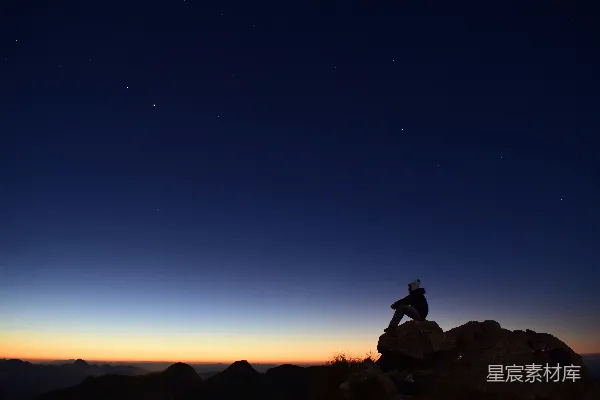 夜晚中一个人坐在岩石上的轮廓