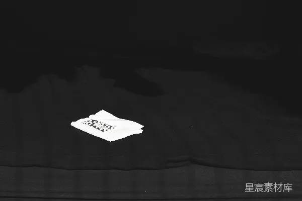 高清摄影 黑色织物上的白色标签，边缘有纹理。