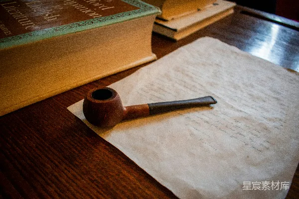 高清摄影 一根木制的管道躺在纸上，旁边是一本书。